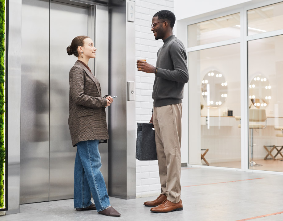 Uma mulher e um homem conversando em quanto esperam o elevador