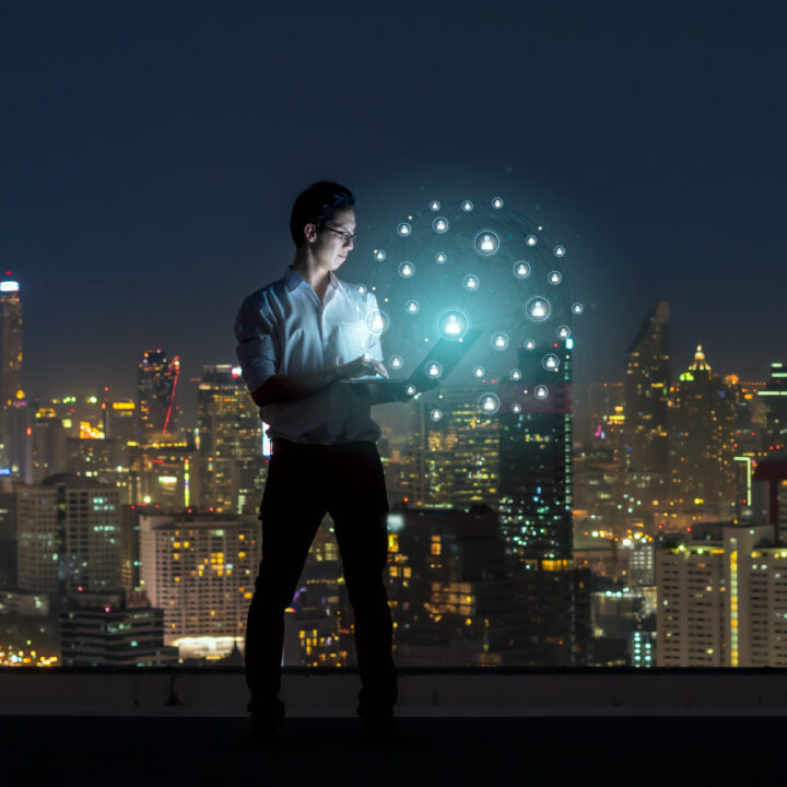 homem acessando uma estrutura digital com a cidade de fundo em uma noite iluminada pela luz da cidade