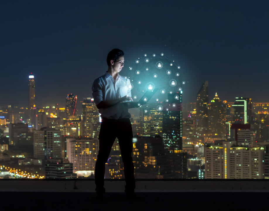 homem acessando uma estrutura digital com a cidade de fundo em uma noite iluminada pela luz da cidade